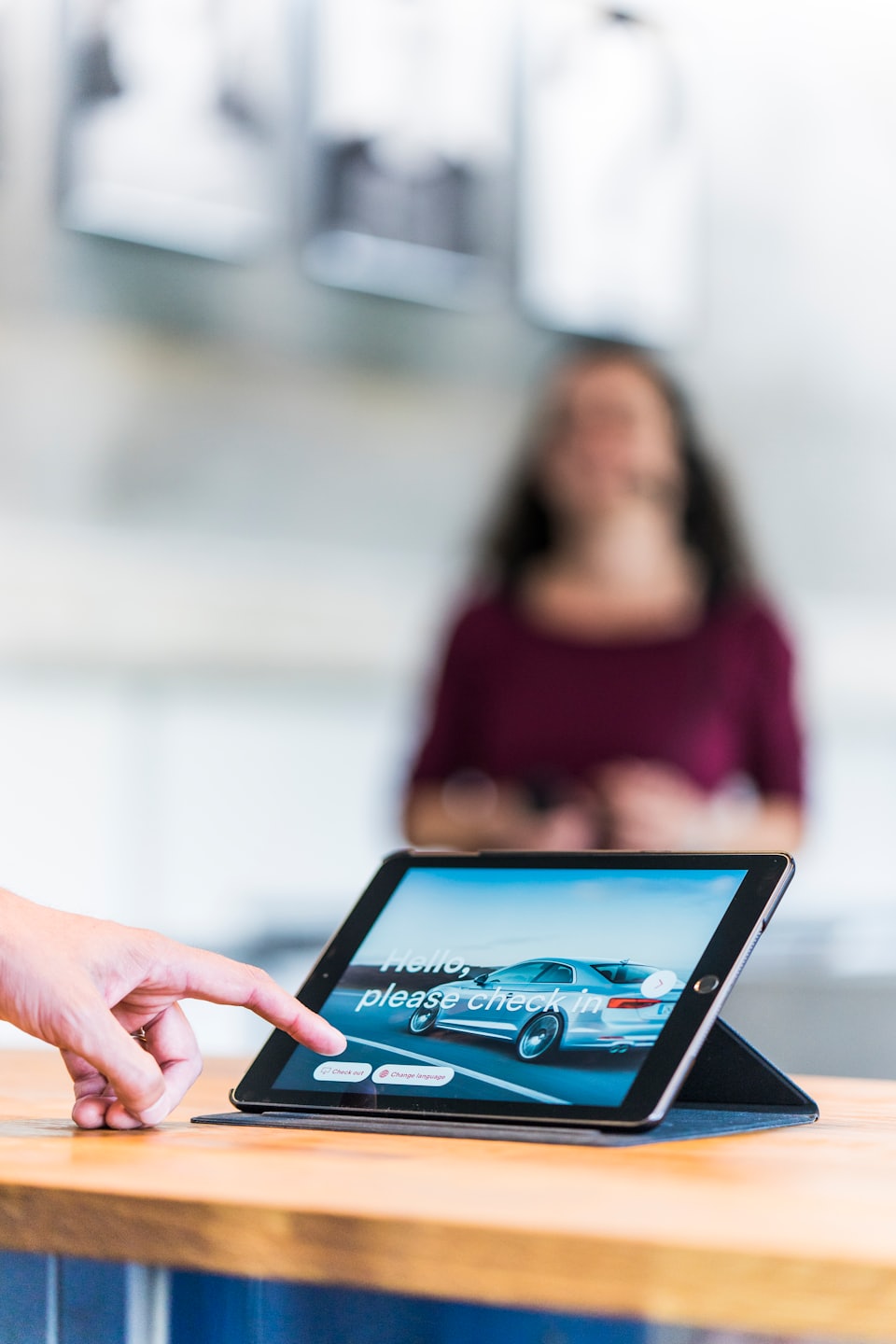 Une main tapote une tablette affichant l'enregistrement numérique d'une voiture.